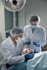 Poster - Doctor and nurse preparing female patient for cosmetic surgery in clinic