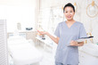 © pressmaster - Portrait of smiling Asian cosmetologist in scrubs standing with clipboard and inviting you to make skin care procedure