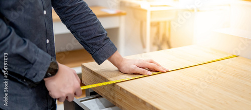 Fotomural Male hand interior designer using tape measure for measuring size of wooden countertop in modern kitchen showroom in furniture store