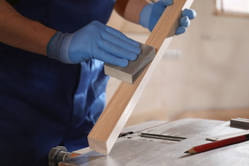 Poster - Professional carpenter polishing wooden bar in workshop, closeup