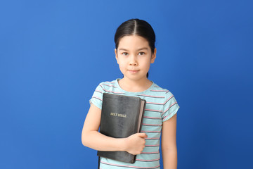 Canvas Print - Cute little Asian girl with Bible on color background