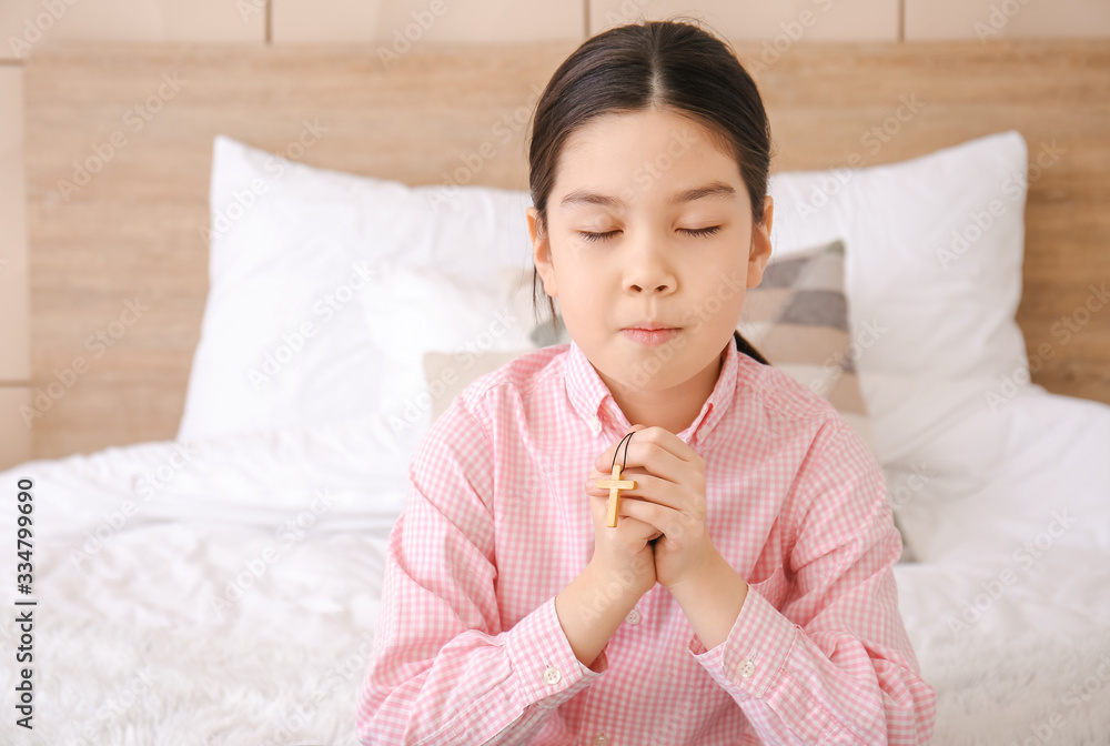 Cute little Asian girl praying at home