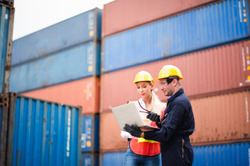 Young Caucasian man and woman worker Check and control loading freight Containers by use computer laptop and radio at commercial shipping dock felling happy. Cargo freight ship import export concept