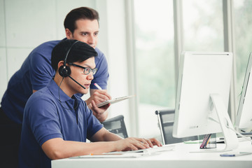 Wall Mural - Young handsome male customer support phone operator with headset working in call center.