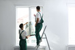 © New Africa - Professional workers tinting window with foil indoors