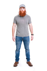 a strong young man with a large beard wearing baseball cap, t-shirt and jeans isolated on a white ba