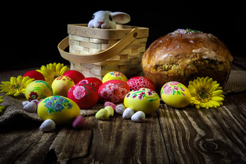 Wall Mural - Traditional holiday composition. Hand painting Easter eggs with orthodox sweet bread on a dark wooden table. With rabbit figure. Selective focus.