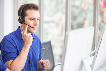 Wall Mural - Young handsome male customer support phone operator with headset working in call center.