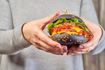 Wall Mural - Female hands hold a black hamburger