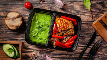 Balanced diet, keto diet. green pea puree, chicken breast with grilled vegetables, mushrooms and paprika. The concept of sports nutrition in disposable eco dishes, top view.