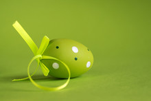 Decorative Green Egg With A Green Satin Ribbon On A Green Background. Easter Concept.