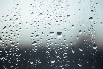 Macro pure rain drops on the glass against a cloud gray background