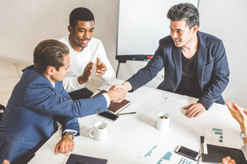 Wall Mural - A team of young office workers, businessmen with laptop working at the table, communicating together in an office. Corporate businessteam and manager in a meeting. coworking.