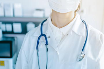 young woman in medical face protection mask and stethoscope indoors on laboratory background