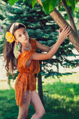 young beautiful stylish girl in red mesh summer tunic and swimsuit walking and posing between trees.