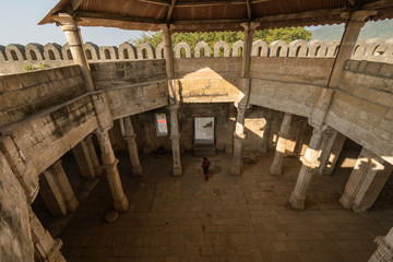 Wall Mural - A wide angle shot of fort walls encircling a large hall with pillars inside the ruins of the ancient Uparkot Fort in the city of Junagadh in Gujarat, India.