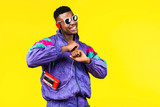 Fototapeta Boho - African American young man, in a jacket in the style of the 90s, with a retro cassette player, hears music, the mood of dancing and fun, yellow and purple colors
