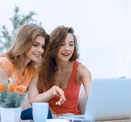 Sticker - two young women discuss the video with laptop sitting at a coffee table