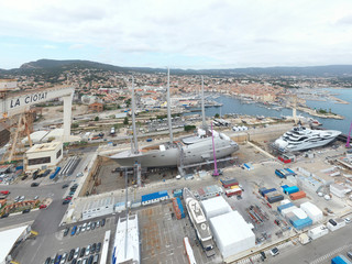 Aerial view of sea dry dock in La Ciotat city, France, the cargo crane, boats on repair, a luxury sail yacht and motor yacht, mountain is on background, shipyard