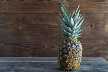 Wall Mural - Fresh pineapple on a wooden table with a wooden phot. Place for text.