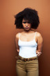 © iordani - pretty young african american woman with curly hair posing cheerful gesturing on brown background, lifestyle people concept