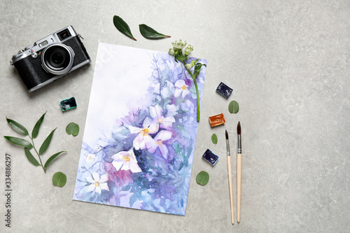 Flat lay composition with watercolor paints and floral picture on grey stone ...