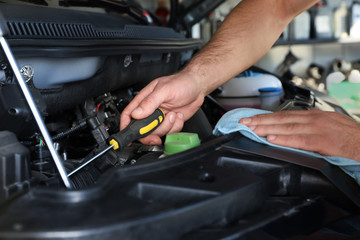 Professional auto mechanic fixing modern car in service center, closeup