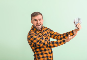 Handsome young man with money on color background