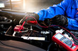 Femal technician uses multimeter voltmeter to check voltage level in car battery. Service and Maintenance car battery.