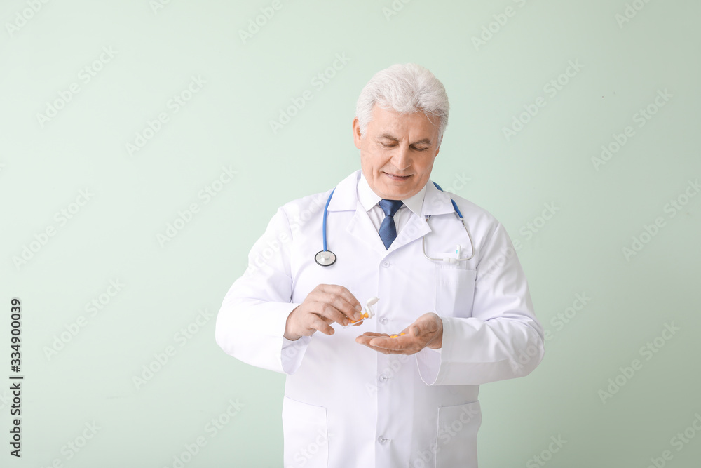 Senior doctor with pills on color background