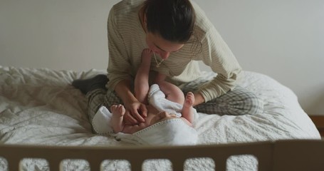 Wall Mural - Authentic shot of a cute newborn baby in a white bathrobe is having fun with his mother after bathing and smiling. Concept of children,baby, parenthood, childhood, life, healthcare, authenticity