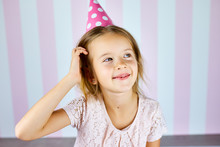 Little Beautiful Girl Wearing Birthday Pink Cap On Pink White Stripe Background.