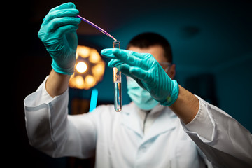 Close-up image of a young chemist holding tubing with liquid during chemical experiment on the lab background