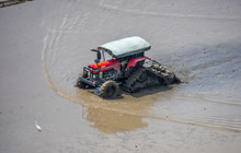 A Tractor Is Doing Its Job Early Mac During The Hot Season In A Paddy Field Fills With Water And Mud. 