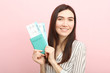 © White bear studio  - Beautiful young smiling girl holds tickets for travel. Rest, travel, tour.