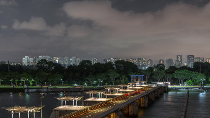 Aerial view Singapore city skyline with bridge at Marina barrage garden night timelapse.