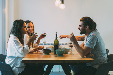 Wall Mural - Old friends enjoying dinner and wine at home. Young men and women in casual meeting indoors. Dining room concept