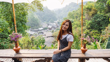 Portrait Image Of A Beautiful Asian Woman Sitting In The Outdoors With The View Of Mae Kampong Village, Chiang Mai, Thailand