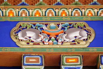 Lhasa, Tibet / China - July 31, 2017: Wooden beams with colorful paintings inside Sera Monastery. Buddhist art depicting two large animals and the jewels of buddhism (buddha, dharma, sangha).