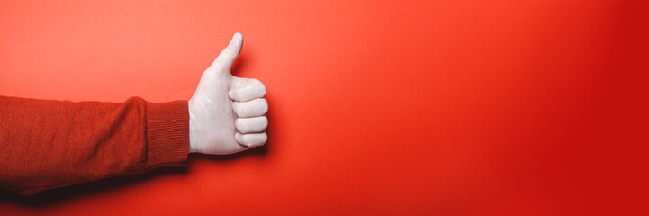 Wall Mural - Male hand in medical glove shows thumb up on red background, banner format, place for text