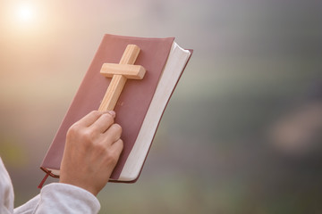 Wall Mural - Girl holding the bible and holding a cross Considered as a sacred blessing of God, spirituality and worship and praise from Christians and religious beliefs for blessings.