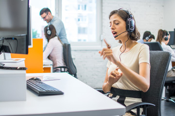 Wall Mural - Beautiful helpline operator woman having online conversation with a client at call center