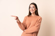 © luismolinero - Young woman over isolated beige background pointing finger to the side