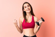 © luismolinero - Young sport woman making weightlifting over isolated pink background pointing to the side to present a product