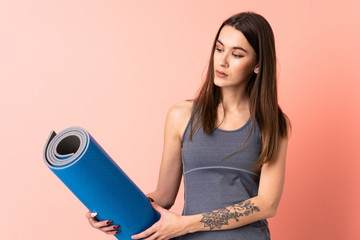 Wall Mural - Young sport woman with mat over isolated background with happy expression