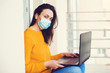 © volurol - Girl working on laptop at balcony during quarantine. Stay home. Coronavirus quarantine. Woman wears protection mask.