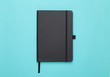 © Touchr - Black notebook isolated on blue background. Flat lay or Top view angle.