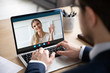 © fizkes - Back view of young businessman sit at workplace talk speak on video call on laptop with smiling wife, male employee husband have online conversation use webcam on computer with happy woman
