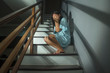 © TheVisualsYouNeed - Asian horror movie style portrait of young adult sad and desperate Chinese woman or teenager girl suffering depression problem or mental disorder sitting on staircase at home