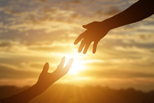 Silhouette Of Giving A Helping Hand, Hope And Support Each Other Over Sunset Background.